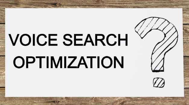 Voice search optimization and a question mark written on a white paper with a wooden background